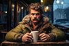 Man with beard sits at table with cup of hot coffee | Stock Foto
