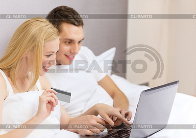 Pareja en la cama con la computadora portátil y la tarjeta de crédito | Foto de alta resolución |ID 4445152