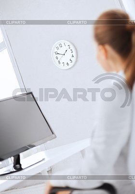 Businesswoman looking at wall clock in office | High resolution stock photo |ID 4459839