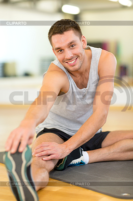 Hombre sonriente que estira en la colchoneta en el gimnasio | Foto de alta resolución |ID 4459922