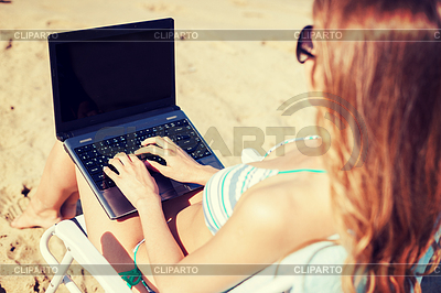 Muchacha que mira en la computadora portátil en la playa | Foto de alta resolución |ID 4461074