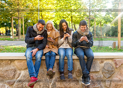 Lächelnde Freunde mit Smartphones im Stadtpark | Foto mit hoher Auflösung |ID 4472971